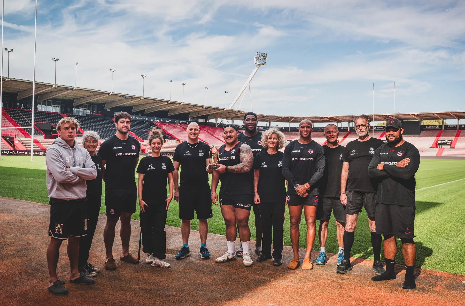 Joueurs et patients posant avec le trophée de la nuit du rugby 25/26